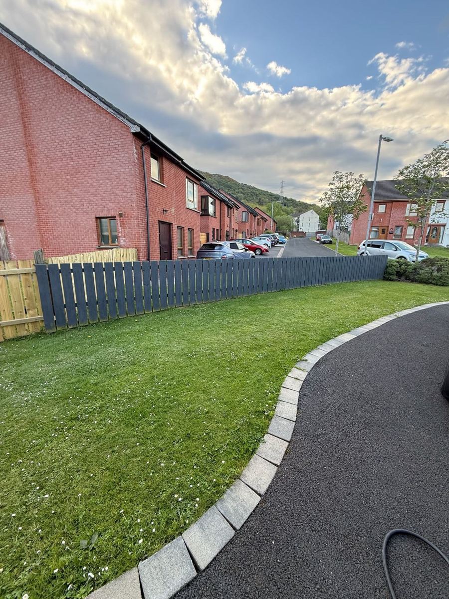 Low grey painted fence along a garden lawn
