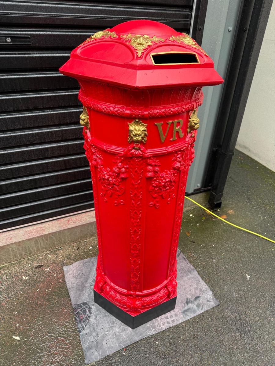 The same post box repainted red with gold lettering and lion heads